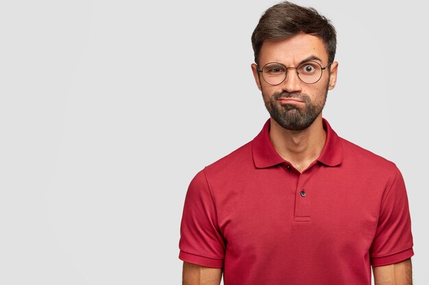 Angry young emotional man posing against the white wall