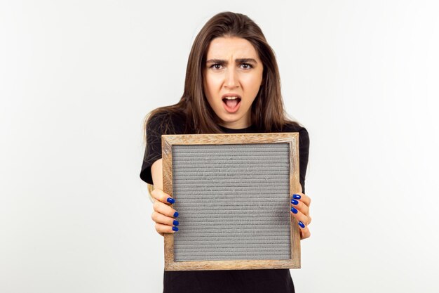 Angry young girl holding board and looking at the camera