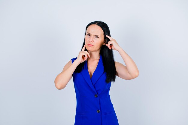 Angry young girl is thinking by holding forefingers around face on white background