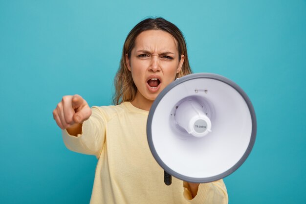 Angry young girl looking and pointing at camera shouting in loud speaker 