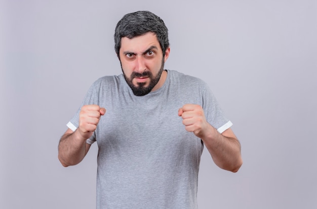 Angry young handsome caucasian man looking with clenched fists isolated on white  with copy space