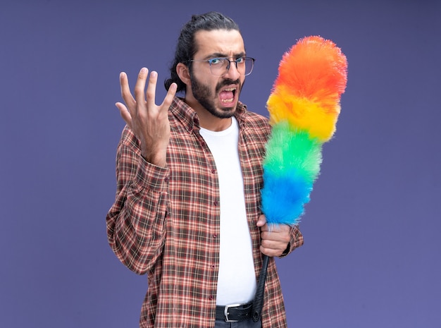 Free photo angry young handsome cleaning guy wearing t-shirt holding pipidaster isolated on blue wall with copy space