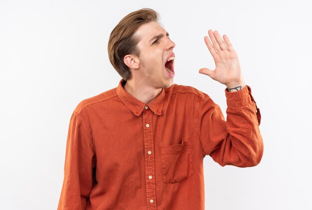 Angry young handsome guy wearing red shirt calling someone isolated on white wall