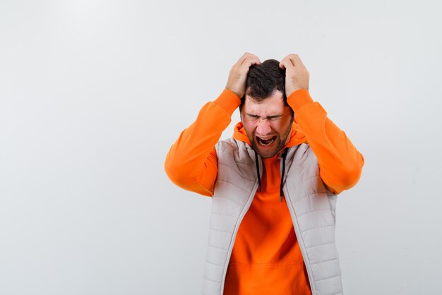 Angry young man screaming on white background