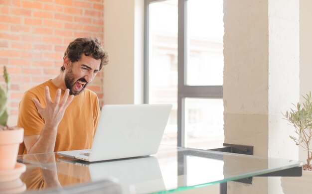 angry young man with a laptop on a desk