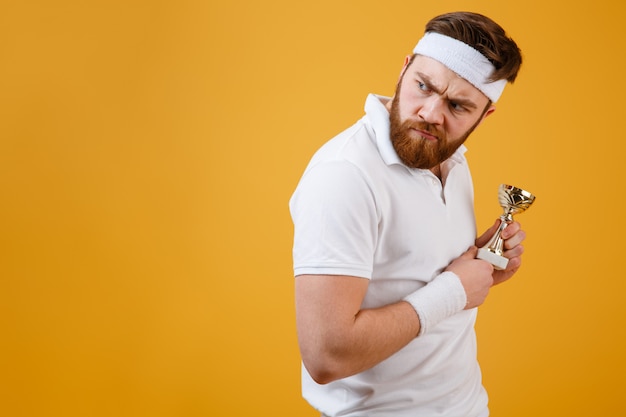 Angry young sportsman with reward looking away.