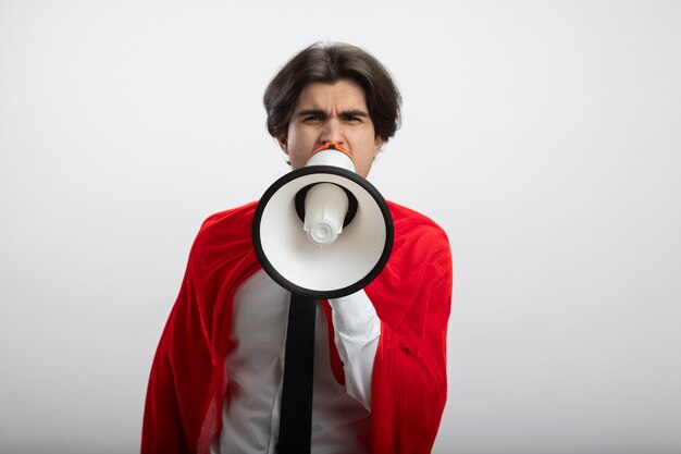 Angry young superhero guy looking at camera wearing tie speaks on loudspeaker isolated on white