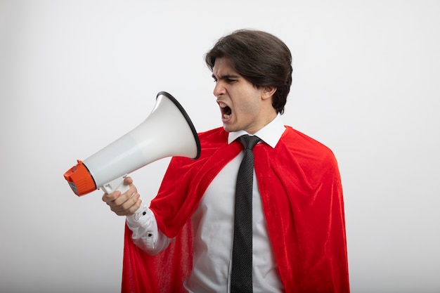 Free photo angry young superhero guy wearing tie speaks on loudspeaker isolated on white background