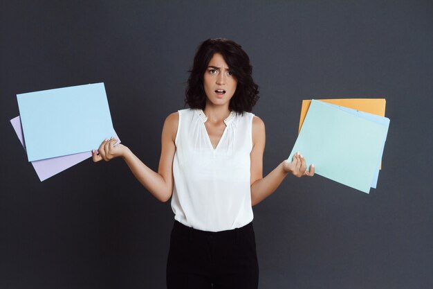 Angry young woman holding documents in hands