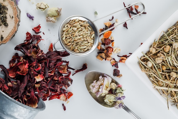 Anise in a small sieve with various dried herbs flat lay on a white surface