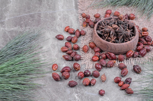 Anise in a wooden cup with dry hips around.