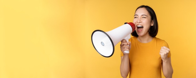 Announcement happy asian woman shouting loud at megaphone recruiting protesting with speaker in hand