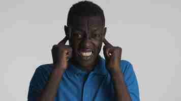 Free photo annoyed african american man emotionally covering ears with fingers and does not want to hear anything isolated on white background so loud expression