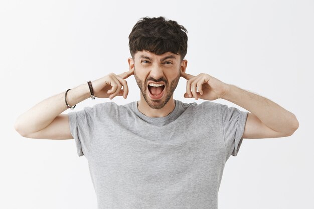 Annoyed and angry handsome guy posing against the white wall