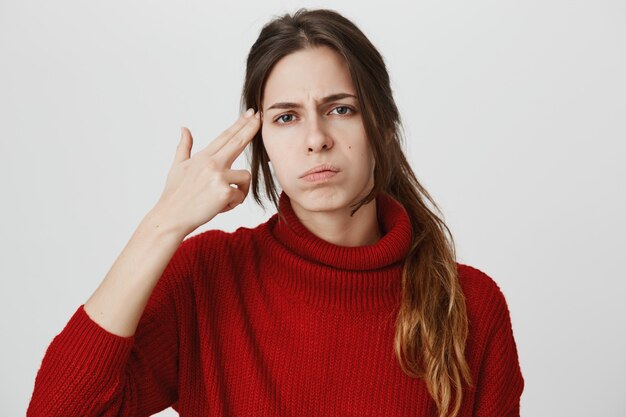 Annoyed or bored girl make gun gesture