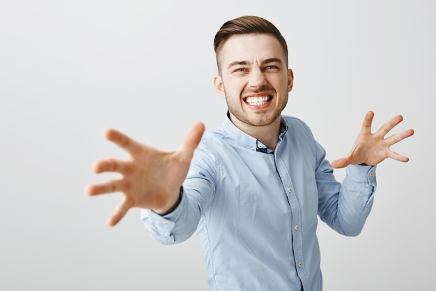 Annoyed businessman look angry reaching hands forward to strangle someone