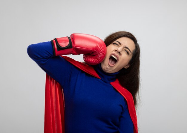 Бесплатное фото Раздраженная кавказская девушка-супергерой в красной накидке в боксерских перчатках