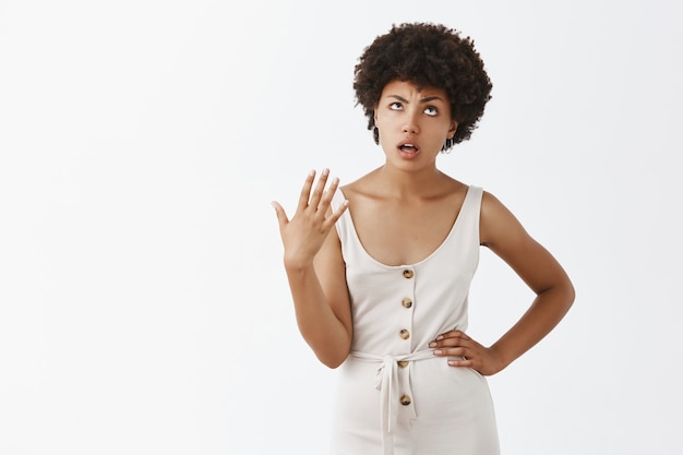 Annoyed and displeased stylish girl posing against the white wall