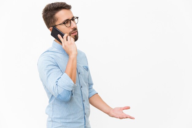 Раздраженный парень разговаривает по мобильному телефону