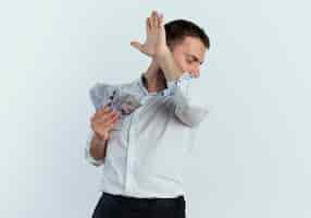 Free photo annoyed handsome man holds money and raises hand hiding face looking at side isolated on white wall