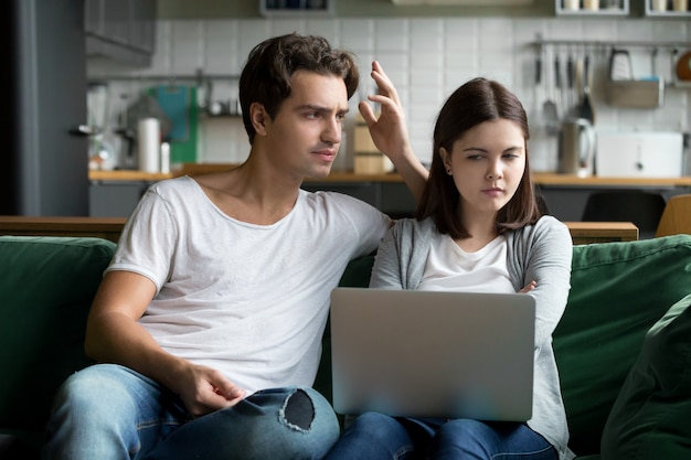 Annoyed husband reproaching frustrated wife wasting money on online shopping 