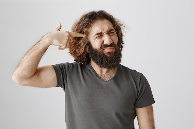 Annoyed middle-eastern guy make fake gun gesture on head, shooting himself from distress