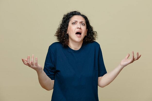 Annoyed middleaged woman wearing tshirt looking at camera showing empty hands isolated on olive green background