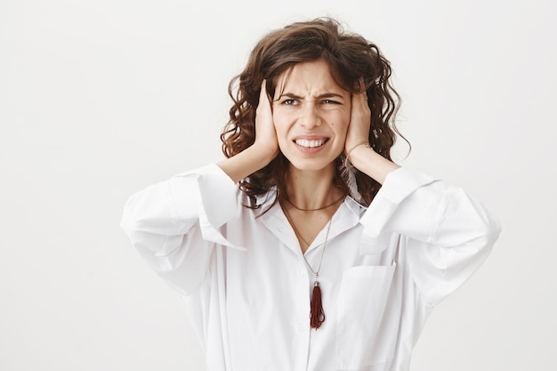 Foto gratuita una donna irritata e incazzata chiuse le orecchie per il rumore forte