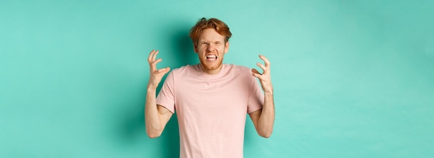 Free photo annoyed and pissedoff redhead guy looking angry shouting and grimacing shaking hands aggressive stan