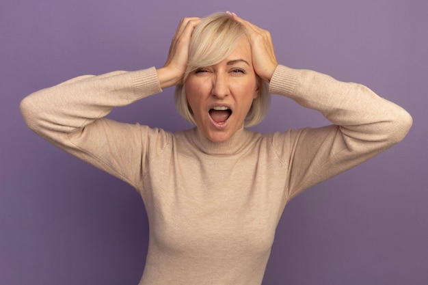 Free photo annoyed pretty blonde slavic woman puts hands on head on purple