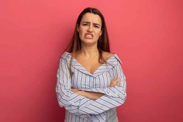 Annoyed pretty caucasian woman stands with crossed arms on pink