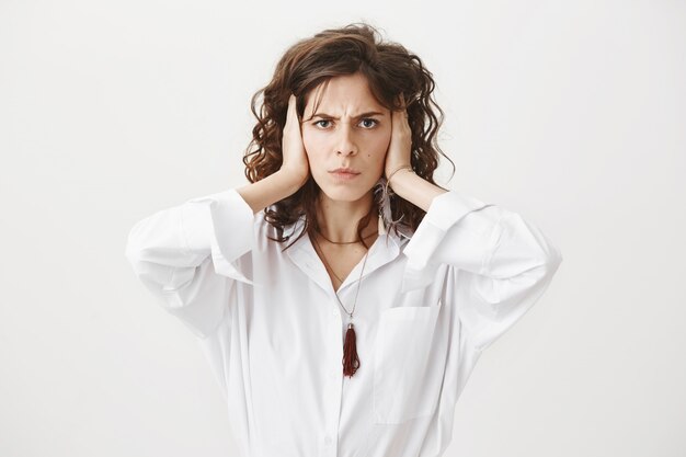 Annoyed sulking woman shutting her ears disturbed