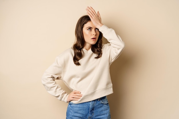 Free photo annoyed woman facepalm roll eyes irritated bothered by smth stupid standing over beige background