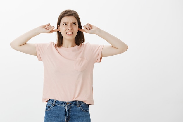 Annoyed woman grimacing from loud noise, shut ears and complaining annoying sound