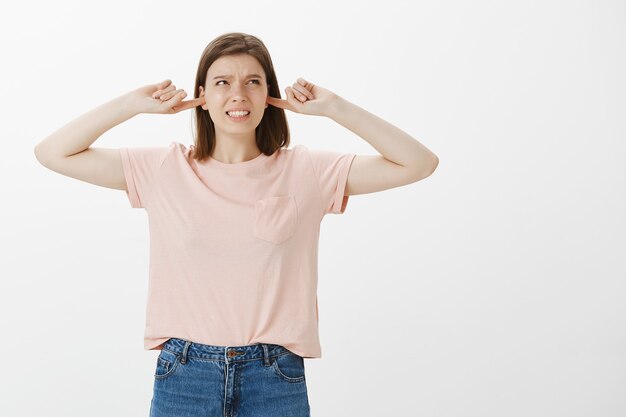 Annoyed woman grimacing from loud noise, shut ears and complaining annoying sound