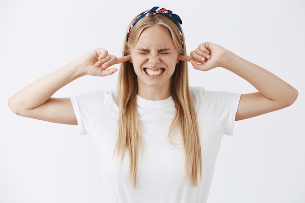 Annoyed young blond girl posing against the white wall