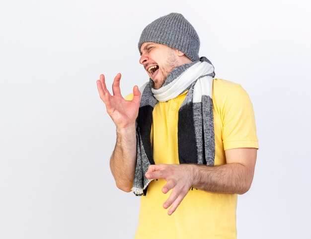 Annoyed young blonde ill slavic man wearing winter hat and scarf