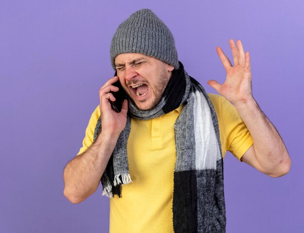 Раздраженный молодой блондин болен славянский мужчина в зимней шапке и шарфе