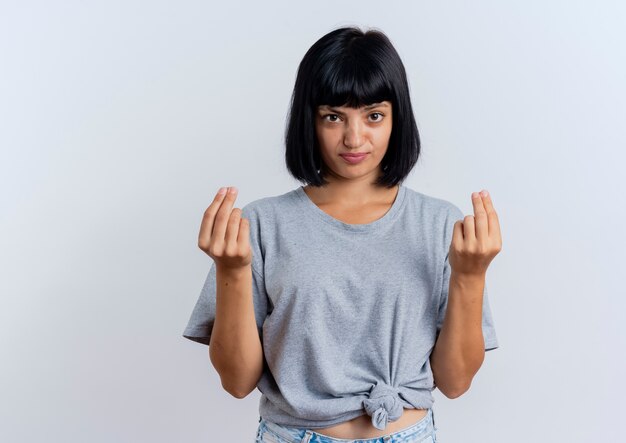 Annoyed young brunette caucasian girl gestures money hand sign with two hands 