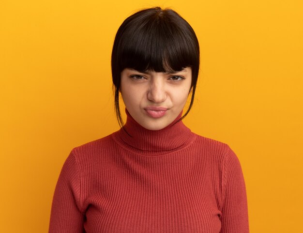 Annoyed young brunette caucasian girl isolated on orange wall with copy space