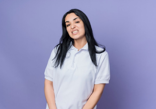 Annoyed young brunette caucasian girl looks isolated on purple wall