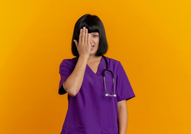 Annoyed young brunette female doctor in uniform with stethoscope