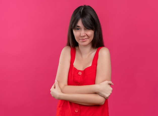 Annoyed young caucasian girl crossing arms and holding with hands looking at camera on isolated pink background with copy space