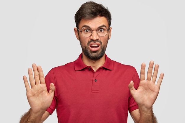 Free photo annoyed young emotional man posing against the white wall