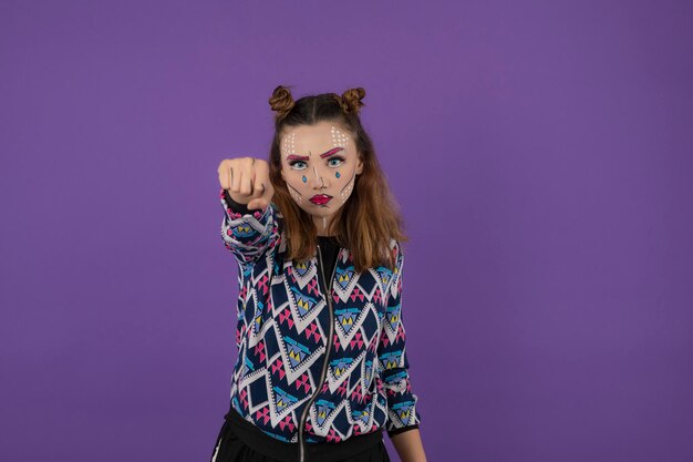 Annoyed young girl with fantasy make up showing her fist to the camera. High quality photo