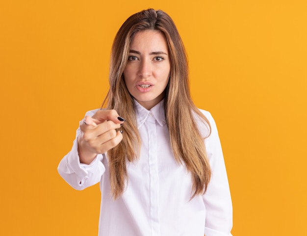 Annoyed young pretty caucasian girl looks and points isolated on orange wall with copy space