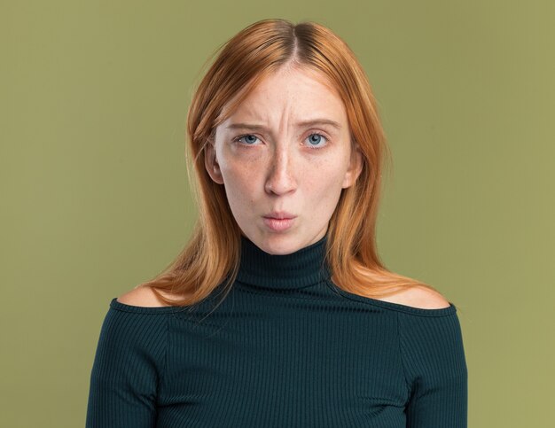 Annoyed young redhead ginger girl with freckles looking at camera