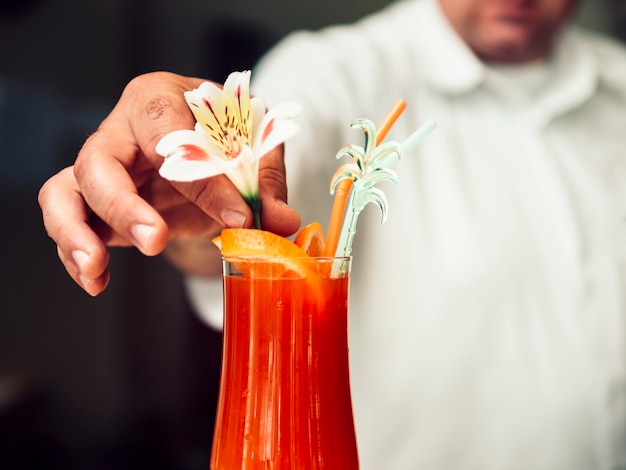 Anonymous bartender serving refreshing drink in glass