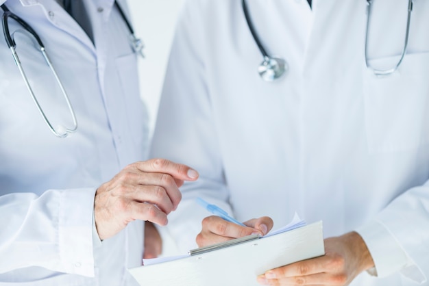Free Photo anonymous doctor helping colleague to write prescription