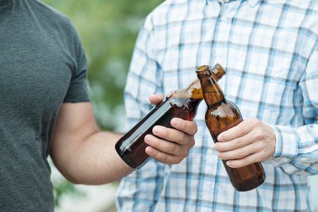 Free photo anonymous friends clinking bottles of beer